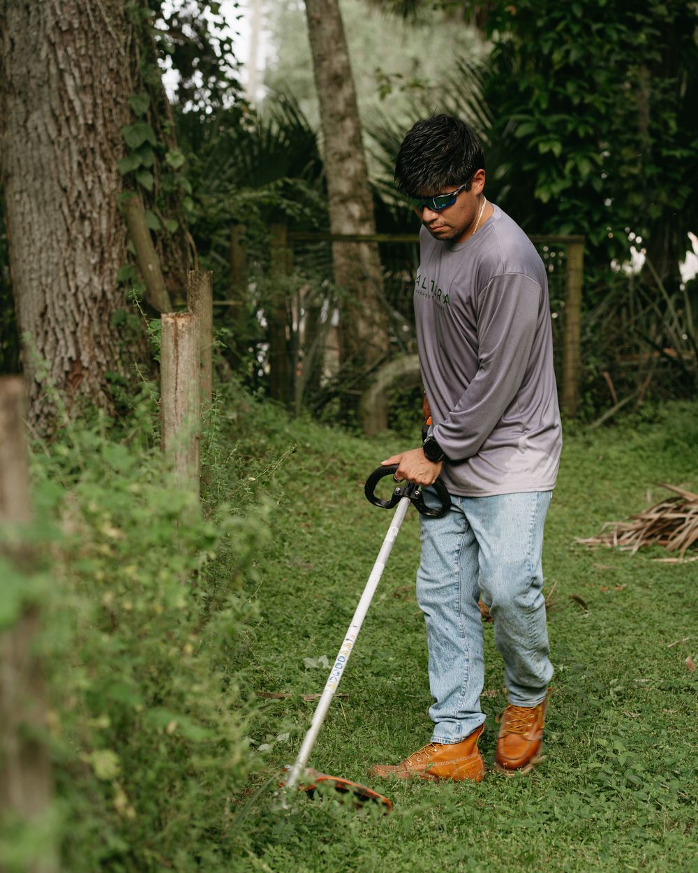 Altura Property Services crew member string trimming along a fence line